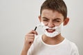 Cropped of dissatisfied boy shaving with razor