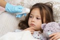 Cropped doctor hand in glove using electronic thermometer against feared sad silent brunette girl. lying with toy in bed