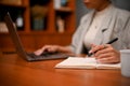 Cropped, Female boss working at her desk, using laptop and writing something on notebook Royalty Free Stock Photo