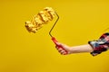 cropped female hand holds paint roller for wall painting  on yellow background Royalty Free Stock Photo