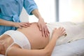 Cropped female physiotherapist doing belly massage to beautiful pregnant woman in spa Royalty Free Stock Photo
