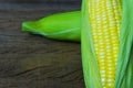 Cropped of fresh sweet corn cobs with leaves on wood table background Royalty Free Stock Photo