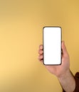 Cropped hand of businessman showing smart phone with blank white screen against beige background. Young male entrepreneur holding Royalty Free Stock Photo
