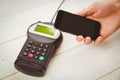 Cropped hand holding mobile phone with credit card reader on table Royalty Free Stock Photo