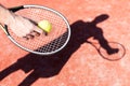 Cropped hand of mature man serving tennis ball on red court during sunny day Royalty Free Stock Photo