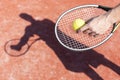 Cropped hand of mature man serving tennis ball on red court during sunny day Royalty Free Stock Photo