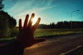 cropped hand of person gesturing on road against sky