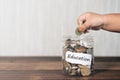 Cropped hand of a toddler putting coin into jar full of coins Royalty Free Stock Photo