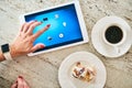 Cropped hand of woman using tablet computer while preparing breakfast