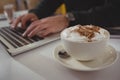 Cropped hands of businessman using laptop by coffee cup Royalty Free Stock Photo