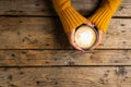 Cropped hands of caucasian woman wearing yellow sweater holding coffee cup over wooden table Royalty Free Stock Photo