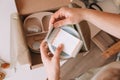 Cropped hands packing, wrapping shipment with silicone baby dishes, plate, spoons, bowl, fixing label to it. Top view Royalty Free Stock Photo