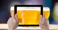 Cropped hands photographing beer glasses through digital tablet at bar Royalty Free Stock Photo