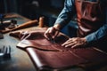 Cropped hands of tailor leather-craftsman working with natural leather, processing cuts leather blanks