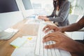 Cropped hands typing on keyboard at computer desk with coworker Royalty Free Stock Photo