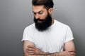 Cropped horizontal portrait of handsome Caucyoung bearded man looking down, on a gray studio background. Portrait of young