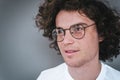 Cropped horizontal view portrait of handsome young male with curly hair, wearing white t-shirt and round trendy spectacles, Royalty Free Stock Photo