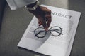 cropped image of african american businesswoman putting glasses on contract in office