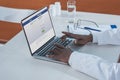 Cropped image of african american doctor sitting with laptop and open