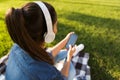 Beautiful young woman student in the park listening music with headphones using mobile phone. Royalty Free Stock Photo