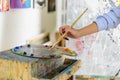 cropped image of artist taking paint from palette