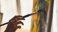 Cropped image of artist woman's hand drawing an oil color on canvas by paint brush at the modern art studio.