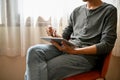 Cropped image of an Asian man using his digital tablet while relaxing on a chair in living room Royalty Free Stock Photo