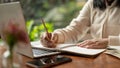 Cropped image of an Asian woman writing something in her book, taking notes while studying online Royalty Free Stock Photo