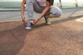 Cropped image of an athlete runner tying shoelaces, standing on a treadmill of the urban glass city bridge, ready for morning jog