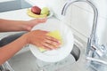 Cropped image of attractive young woman is washing dishes while doing cleaning at home Royalty Free Stock Photo