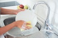 Cropped image of attractive young woman is washing dishes while doing cleaning at home Royalty Free Stock Photo