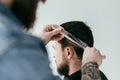 cropped image of barber cutting customer hair with scissors and comb at barbershop Royalty Free Stock Photo