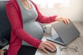 Cropped image of beautiful pregnant business woman closing a laptop and holding one hand on mouse while finishing working from hom Royalty Free Stock Photo