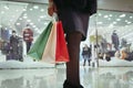 Cropped image of beautiful woman holding shopping bags after doing shopping in female boutique. Bottom-up view to woman