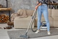 Cropped image of beautiful young woman using a vacuum cleaner while cleaning carpet in the house Royalty Free Stock Photo