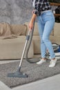 Cropped image of beautiful young woman using a vacuum cleaner while cleaning carpet in the house Royalty Free Stock Photo