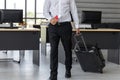 Cropped image of business man holding passport and luggage in workplace of office. Summer vacations concept Royalty Free Stock Photo