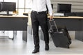 Cropped image of business man holding passport and luggage in workplace of office. Summer vacations concept Royalty Free Stock Photo