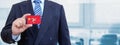 Cropped image of businessman holding plastic credit card with printed flag of Isle of Man. Background blurred