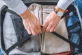 cropped image of businessman with wristwatch packing luggage