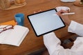 Cropped image of creative woman`s hand holding/using a stylus pen to drawing on white blank screen computer tablet that putting o Royalty Free Stock Photo