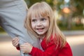 Cropped image of cute little girl looking at camera while hugging her father's leg not letting him go Royalty Free Stock Photo