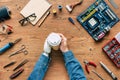 cropped image of electronic engineer with prosthetic arm holding paper cup on table