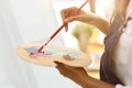 Cropped image of female artist holding and mixing colour on art palette Royalty Free Stock Photo
