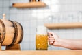 cropped image of female bartender putting mug of light beer with foam on bar counter with beer Royalty Free Stock Photo