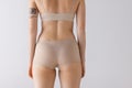 Cropped image of female body, back buttocks in beige underwear isolated over grey studio background. Medical care .