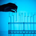 Cropped image of female chemist taking glass tube with substance from stand