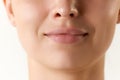 Cropped image of female face, lips and nose over white background. Lip augmentation and anti-wrinkle fillers