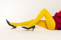 Cropped image of female legs in yellow bright tights and heels  over grey studio background Royalty Free Stock Photo
