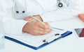 Cropped image of female medicine doctors hands filling patient medical form.